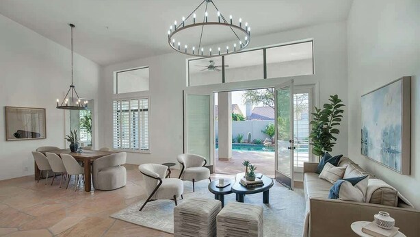A spacious living room with a dining area, a chandelier, a large window, and a view of a pool. - Princess Views-Pool & Spa-Walk to TPC Scottsdale (Scottsdale)