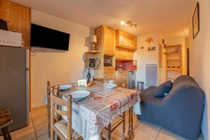 Eine kleine Küche mit Holzausstattung, einem Esstisch für zwei Personen und einem blauen Sofa.