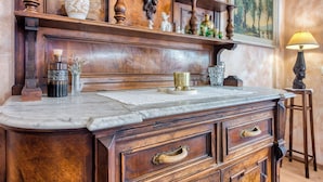 A wooden vanity with a marble countertop, a framed painting on the wall, and a lamp. - Vila Leonarda with Terrace and Garden, Miren, Slovenia (Miren)
