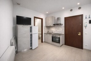 Eine kleine Küche mit Kühlschrank, Backofen und Mikrowelle.