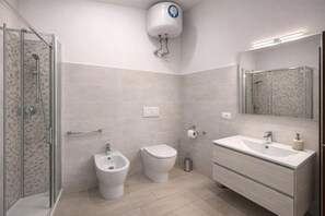 Un baño moderno con cabina de ducha de vidrio, un bidé, un inodoro y un lavamanos con tocador.