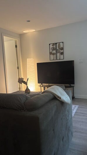 Un salon moderne avec un canapé, un téléviseur à écran plat et des œuvres d’art décoratives au mur.