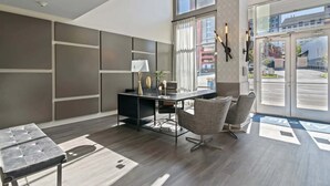 A modern hotel lobby with a reception desk, seating area, and large windows offering views of the street. - Boulevard Stays Midtown 30ft Ceilings 1BR 01 (Nashville)