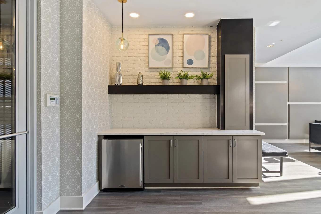 Una cocina moderna con un refrigerador de acero inoxidable, armarios grises, una encimera negra y una lámpara colgante.