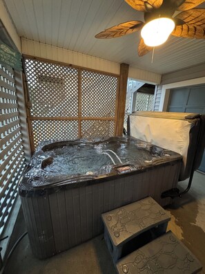 Un bain à remous avec une terrasse en bois, un ventilateur de plafond et un radiateur fixé au mur.
