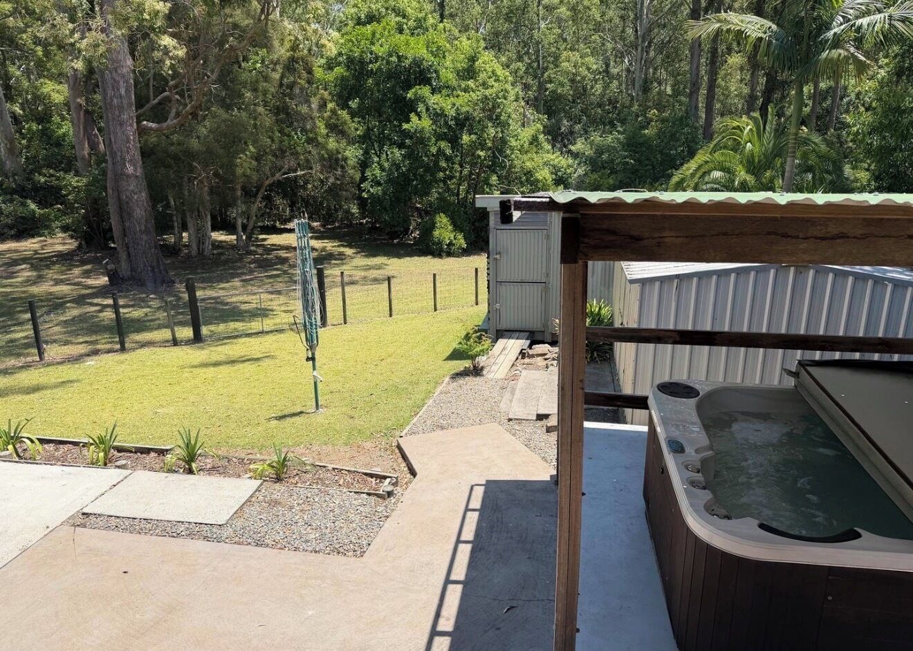 A hot tub, a small shed, and a grassy yard with trees.