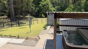 A hot tub, a small shed, and a grassy yard with trees.