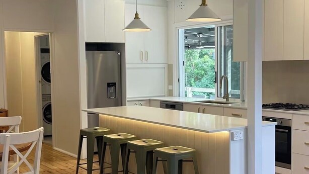 Una cocina moderna con una isla central, taburetes de bar y vistas al exterior.