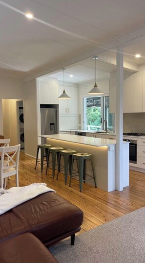 Una cocina moderna con una isla central, taburetes de bar y vistas al exterior.