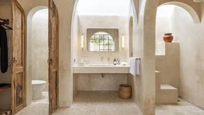 A bathroom with a large arched window, a sink with a mirror, and a rustic wooden door. - Bohemian 2BR Private Suites By Orivista (Kerobokan)