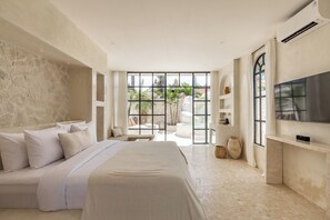 A modern bedroom with a large bed, a TV, and a view of the outdoors. - Bohemian 2BR Private Suites By Orivista (Kerobokan)