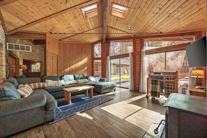 A spacious living room with a large sectional sofa, a fireplace, and a stone wall. - Rare Indoor Pool, Game Room & Courts, 5 Blocks to Snow Summit (Big Bear Lake)