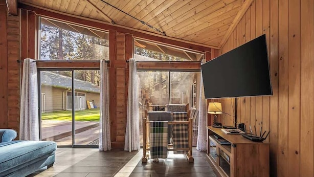 En inredning med träpanel, en soffa, en tv och ett bord med en lampa.