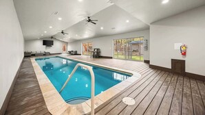 En inomhuspool med takfläktar, en brandsläckare och utsikt över omgivningen.