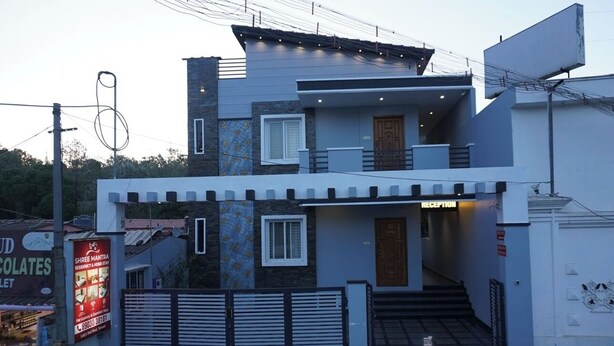 A modern two-story house with a reception area, a gated entrance, and a sign for a chocolate shop. - Shree Mantra Residency  (Yercaud)