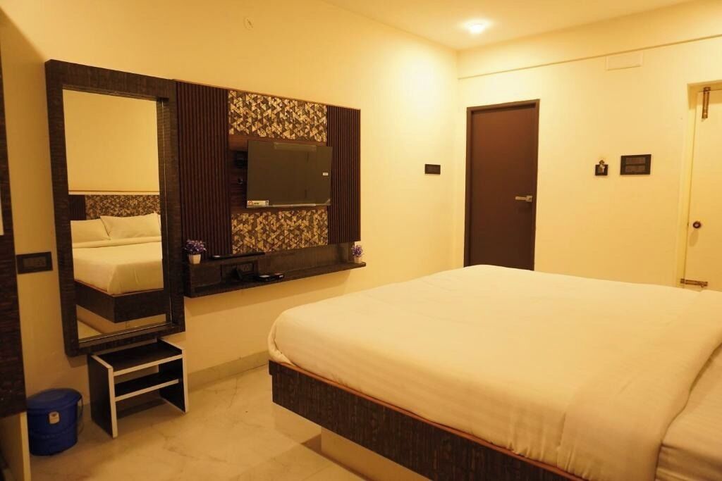 Una habitación de hotel con una cama grande, un espejo, una televisión y una puerta.