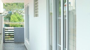 A narrow corridor with a balcony on one side, leading to a door with a window. - Shree Mantra Residency  (Yercaud)