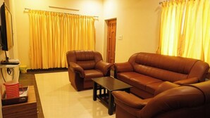 A living room with a brown leather sofa, a matching armchair, and a small coffee table. - Shree Mantra Residency  (Yercaud)