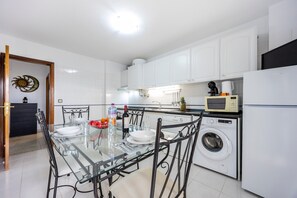 Una cocina moderna con una mesa de comedor de vidrio, lavadora y microondas.