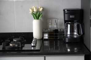 A kitchen counter with a white vase of tulips, a coffee maker, and a glass carafe.