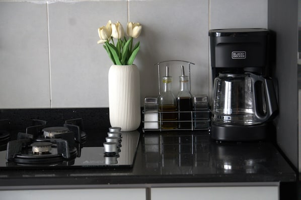 A kitchen counter with a white vase of tulips, a coffee maker, and a glass carafe.