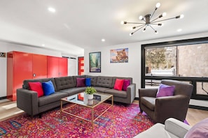 Una sala moderna con un sofá modular, una mesa de centro de vidrio y una alfombra estampada.