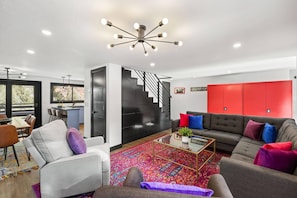 Una sala de estar moderna con un sofá, una mesa de centro y una escalera que lleva a una cocina.