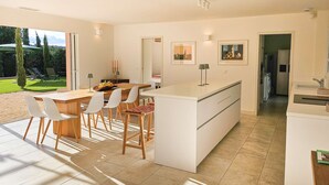 Una cucina moderna con isola centrale, mobili bianchi e un'area pranzo con tavolo e sedie.
