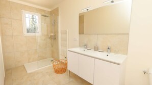 Un bagno moderno con doccia a pavimento, uno specchio grande e un mobile lavabo bianco con due lavabi.