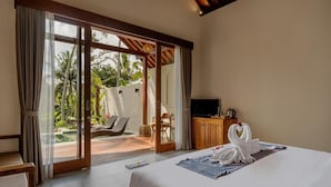 Ein Hotelzimmer mit Bett, Fernseher, Holzschrank und Blick auf Pool und Palmen.