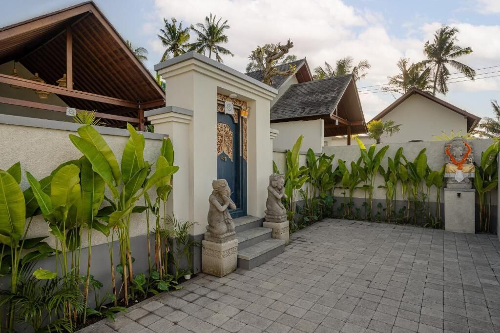 Uma casa tradicional com um pátio ladrilhado, uma porta azul e estátuas de pedra.