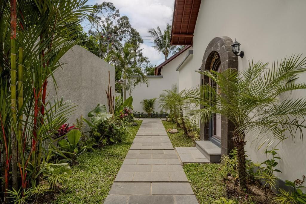 A narrow stone pathway leading to a building with a stone archway and a lantern.