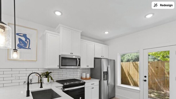 A modern kitchen with white cabinetry, a stainless steel refrigerator, a microwave, and a gas stove. - Spacious Modern Home w/ Smart Entry (Houston)