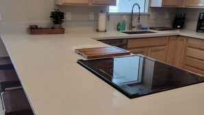 A modern kitchen with a large island, wooden cabinets, and a stainless steel sink. - Four Bedroom Home with Swimming Pool and Game Room (Lake Havasu City)