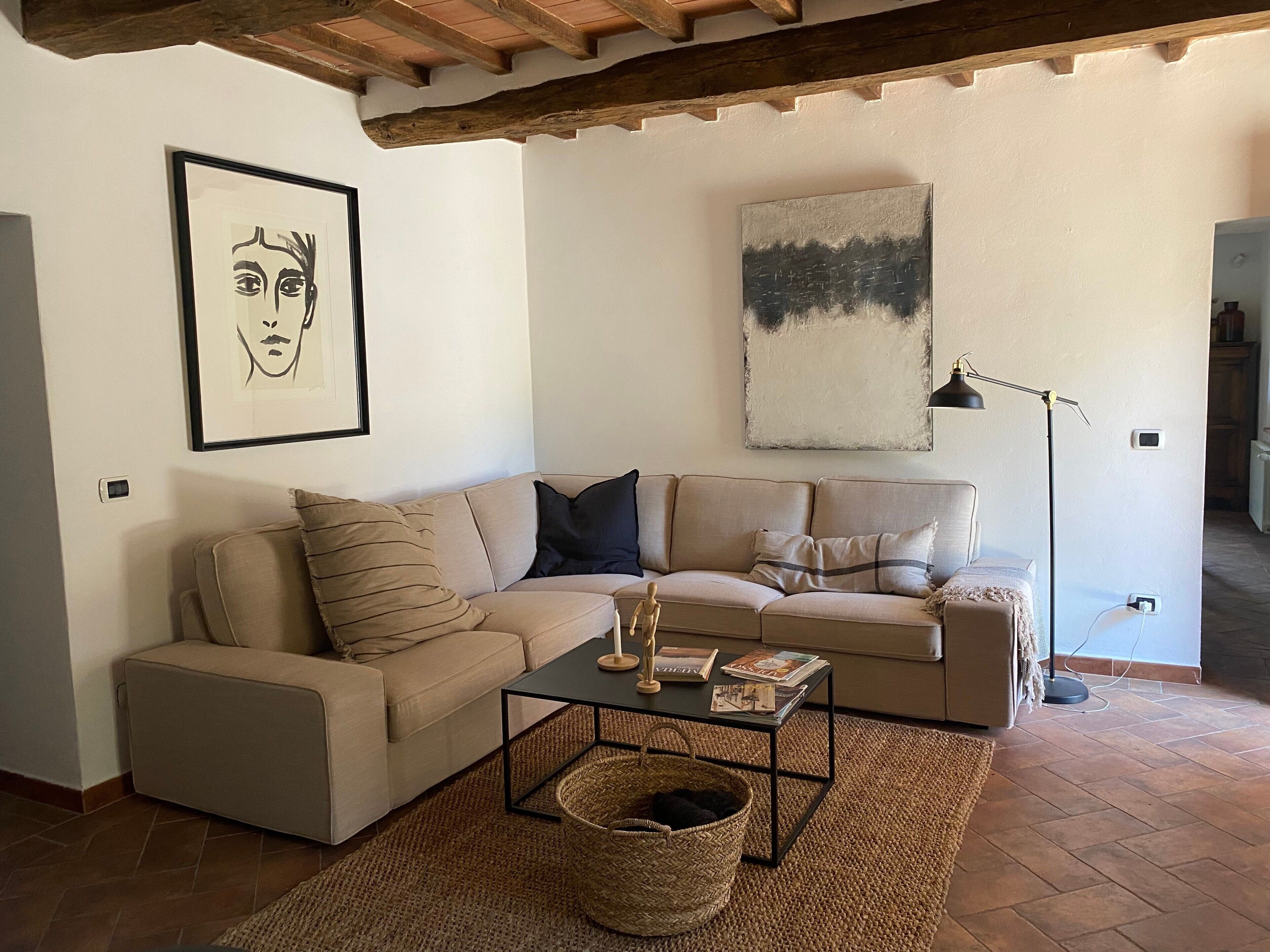 Ein Wohnzimmer mit einer Couch, einem Couchtisch, einer Lampe und Kunstwerken an den Wänden.