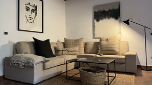 Una sala de estar moderna con un sofá seccional, una mesa de centro, una lámpara de pie y una obra de arte enmarcada en la pared.