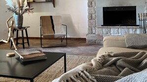 Una sala de estar acogedora con chimenea, techo de madera y pared de piedra.