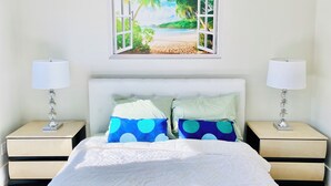 A bedroom with a bed, two nightstands, and a wall-mounted picture of a beach scene. - 5-bedroom whole apartment perfect for groups 1/2 block from San Francisco Border (Daly City)