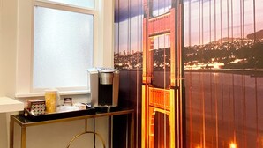 A room with a large window, a desk with a coffee machine, and a view of the Golden Gate Bridge. - 5-bedroom whole apartment perfect for groups 1/2 block from San Francisco Border (Daly City)