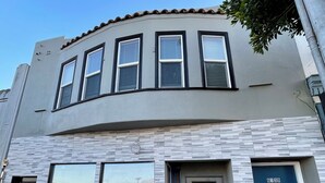 A two-story building with a curved facade, large windows, and a blue door. - 5-bedroom whole apartment perfect for groups 1/2 block from San Francisco Border (Daly City)