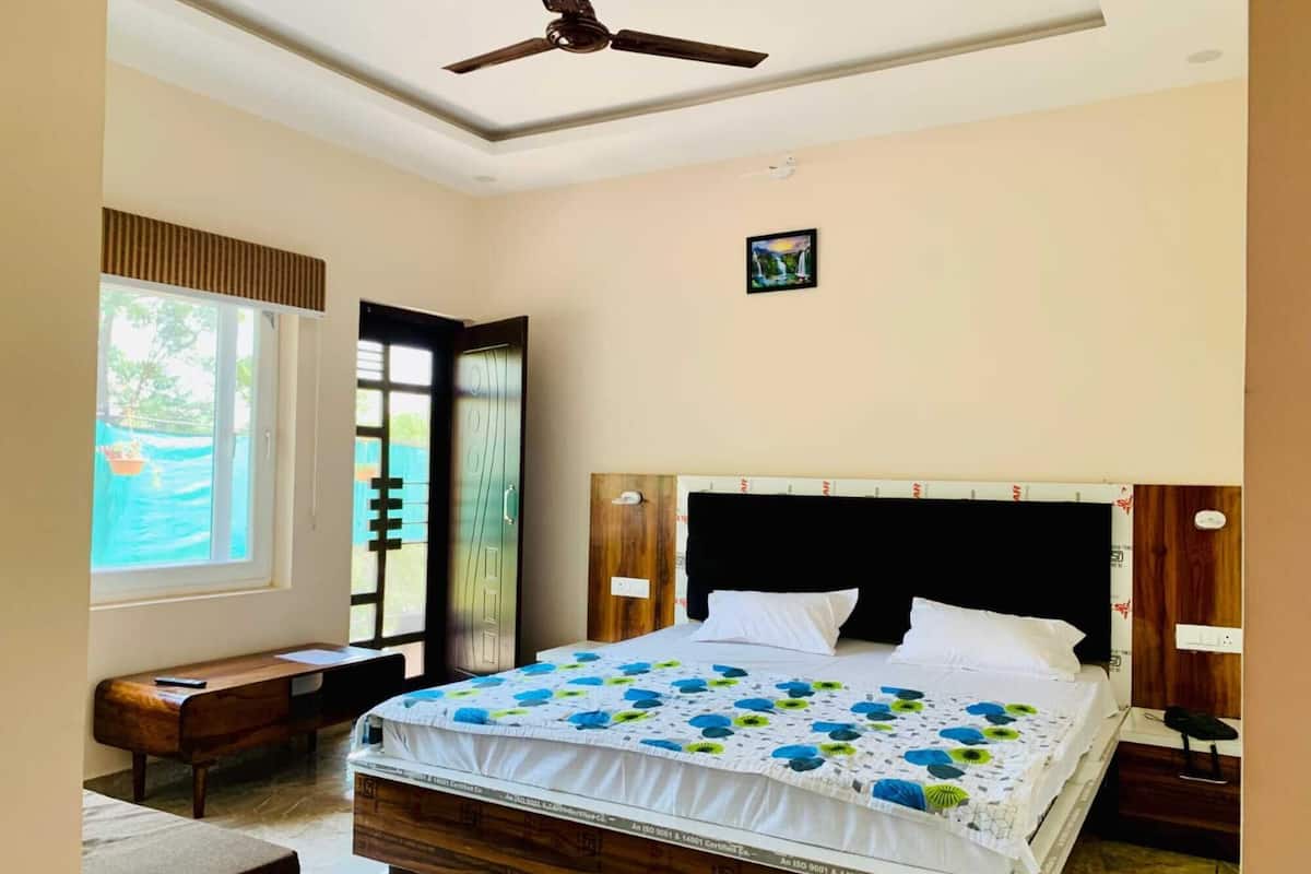 Une chambre à coucher comprenant un lit, un bureau, une chaise, un ventilateur de plafond, une fenêtre et une porte.