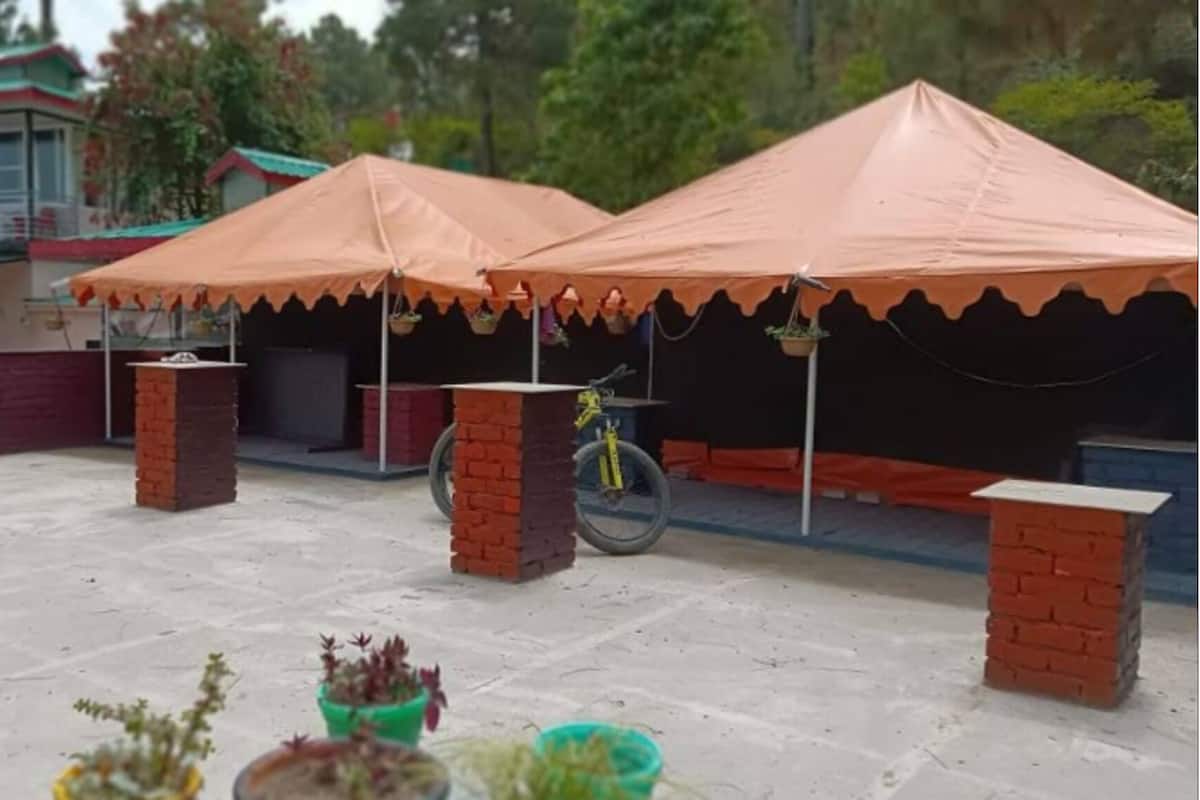 Un espace extérieur abrité, avec deux piliers en briques, un vélo et des plantes en pot.