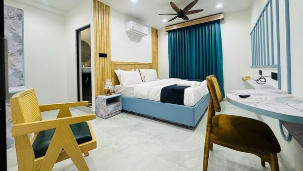 A modern hotel room with a bed, a desk, and two chairs. - The 5 Story (Hyderabad)
