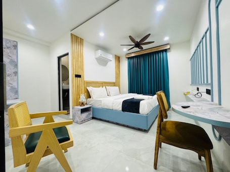 A modern hotel room with a bed, a desk, and two chairs.