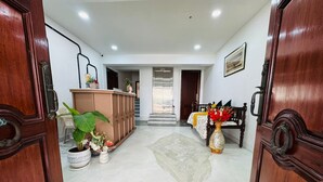 A hotel lobby with a reception desk, a reception area, a seating area with a bench, and a staircase leading to another floor. - The 5 Story (Hyderabad)