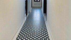 A hallway with patterned flooring and recessed lighting. - The 5 Story (Hyderabad)