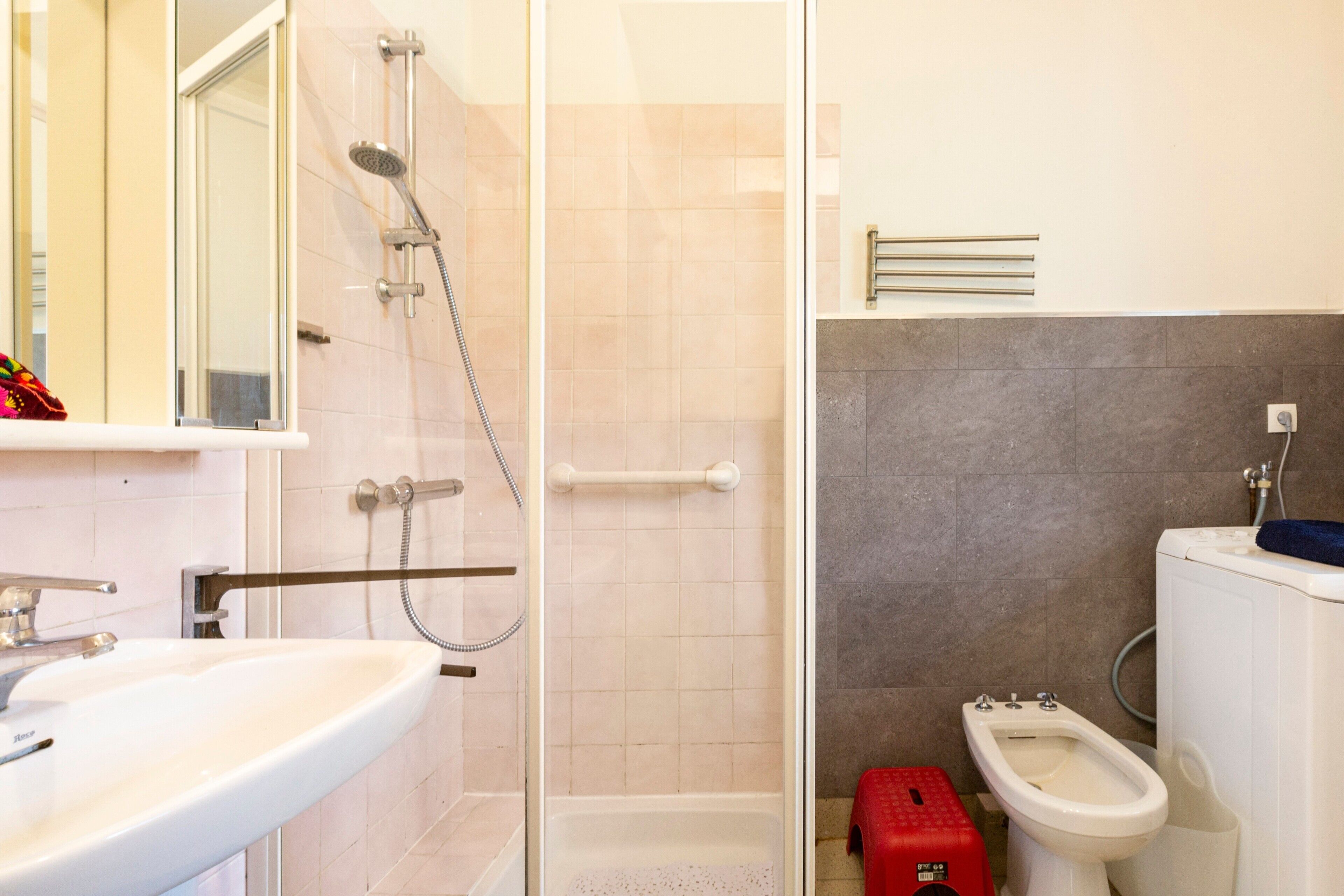 A bathroom with a shower, toilet, bidet, and sink.