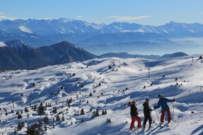 A snowy mountain landscape with skiers, clear skies, and distant snow-capped peaks. - Le gite à Géo – Charming Renovated House with Space, Authenticity, and Nature (Thoiry)