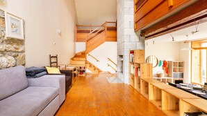 A spacious living area with a wooden staircase, a sofa, and a dining table.