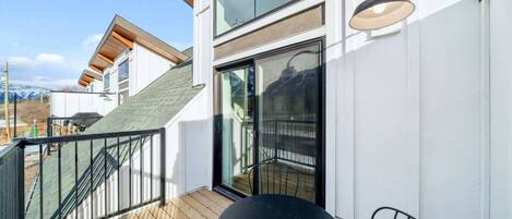 A modern building with a wooden deck, a black table, and a chair.